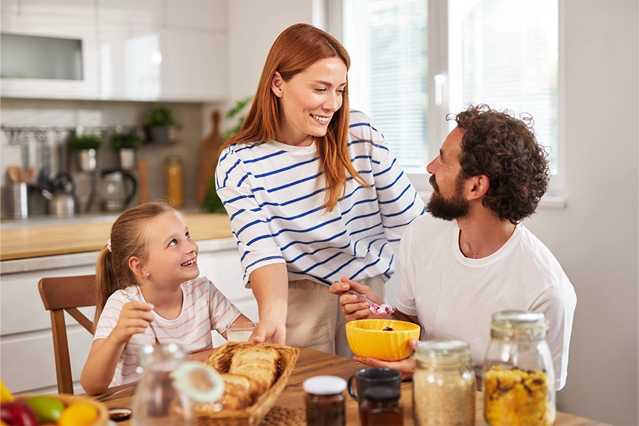mother, father, daughter eating breakfast on table with cereal